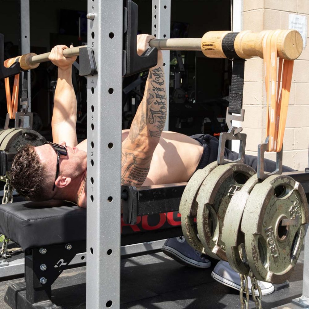 man benching with earthquake bar outside