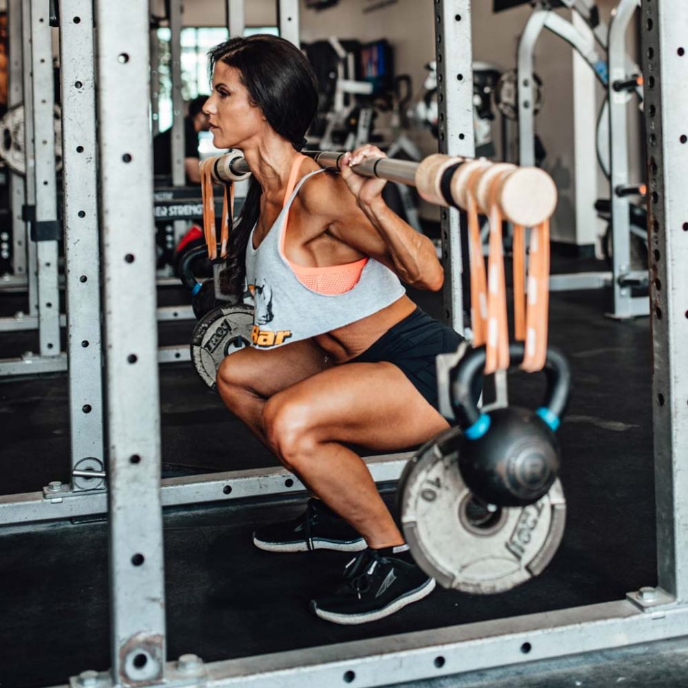 woman at bottom of squat with loaded earthquake bar